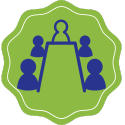 ID: Blue icon of people at a board room table, with a green background